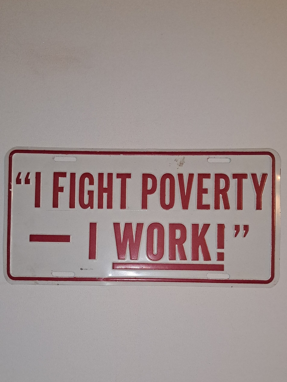Decorative White License Plate Sign with Red Text - "I FIGHT POVERTY - I WORK!"